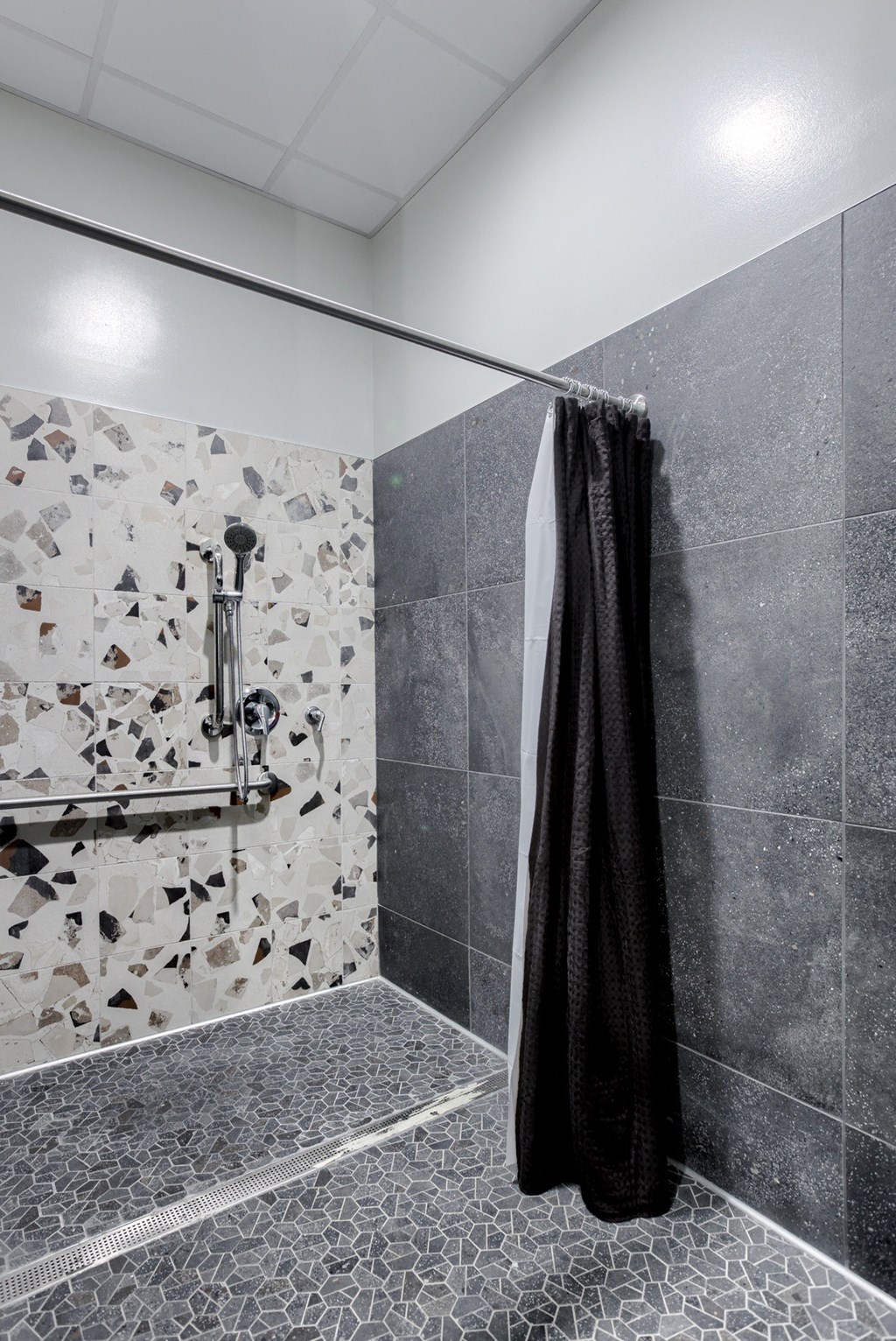 the shower in this bathroom has a shower curtain that is made of black and white peb