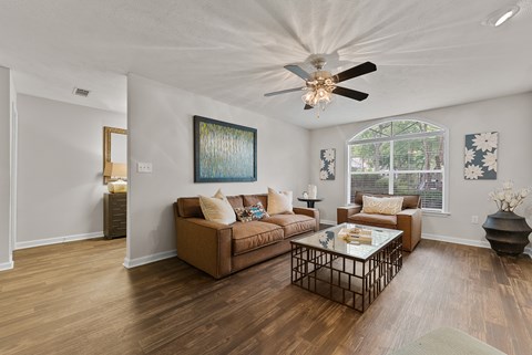 A living room with a brown couch and a painting on the wall.