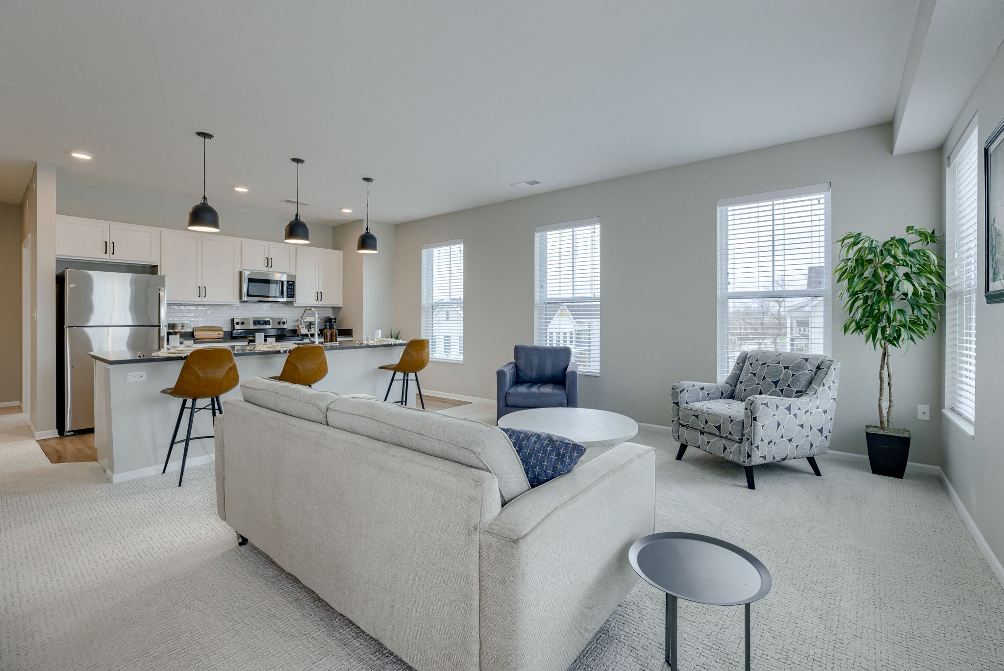 an open living room and kitchen with a couch and chairs