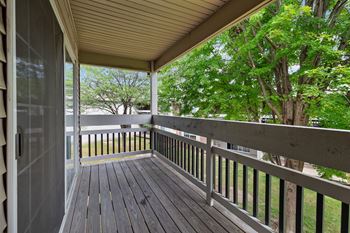 A wooden deck with a railing and trees in the background.