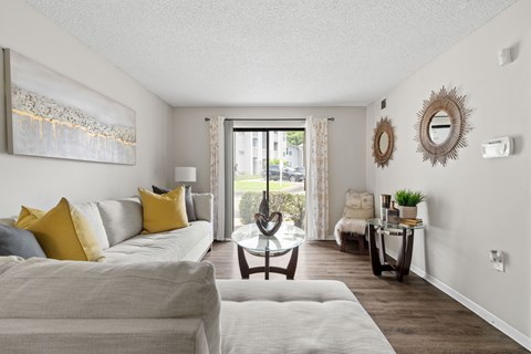 A living room with a grey couch and a painting on the wall.