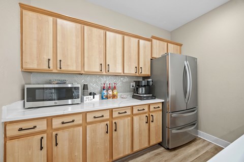 A kitchen with wooden cabinets and a stainless steel refrigerator.
