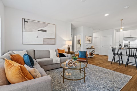 A living room with a grey couch, a coffee table, and a painting on the wall.