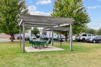 A wooden pavilion with a green table underneath it.