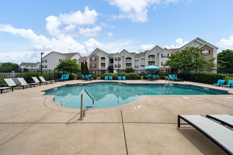 A swimming pool surrounded by a concrete floor and a black fence.