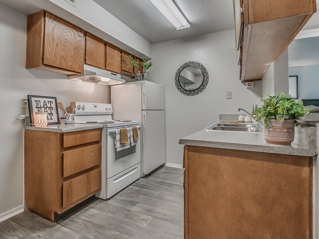 Galley Kitchen With White Appliances & Wood-Style Flooring