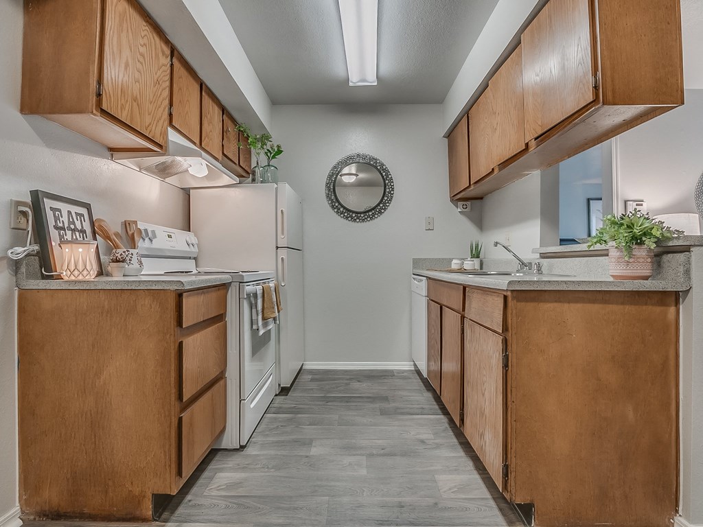Galley Kitchen Featuring White Appliances & Oak Cabinetry