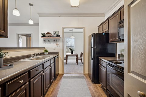 A kitchen with dark brown cabinets and a black refrigerator.