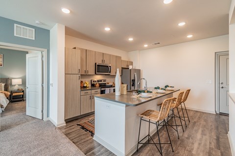 a kitchen with a island and a bar with three chairs