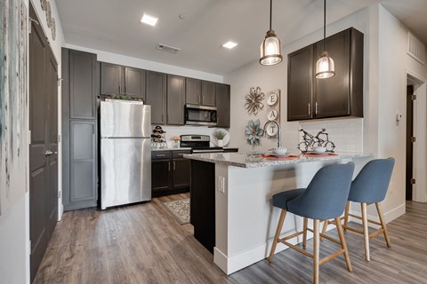 a kitchen with stainless steel appliances and a counter with two stools