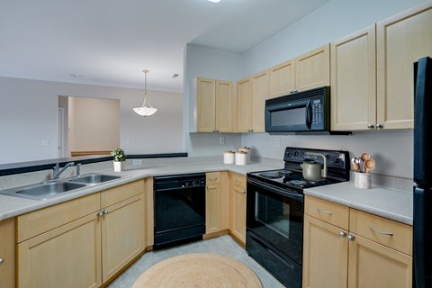 A kitchen with wooden cabinets and black appliances.