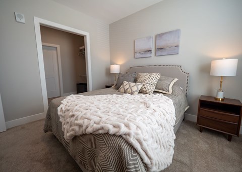 A bedroom with a large bed covered in a white knit blanket.