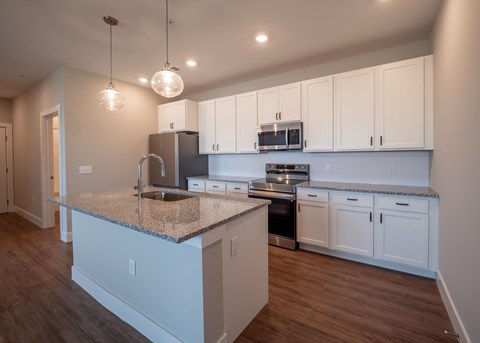 A kitchen with white cabinets and a granite countertop.