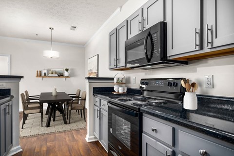 a kitchen with a stove and microwave and a dining room table
