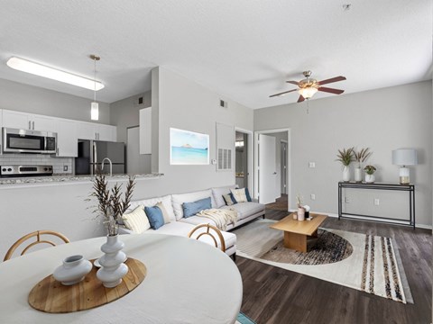 A modern living room with a white dining table and a white sofa with blue pillows.