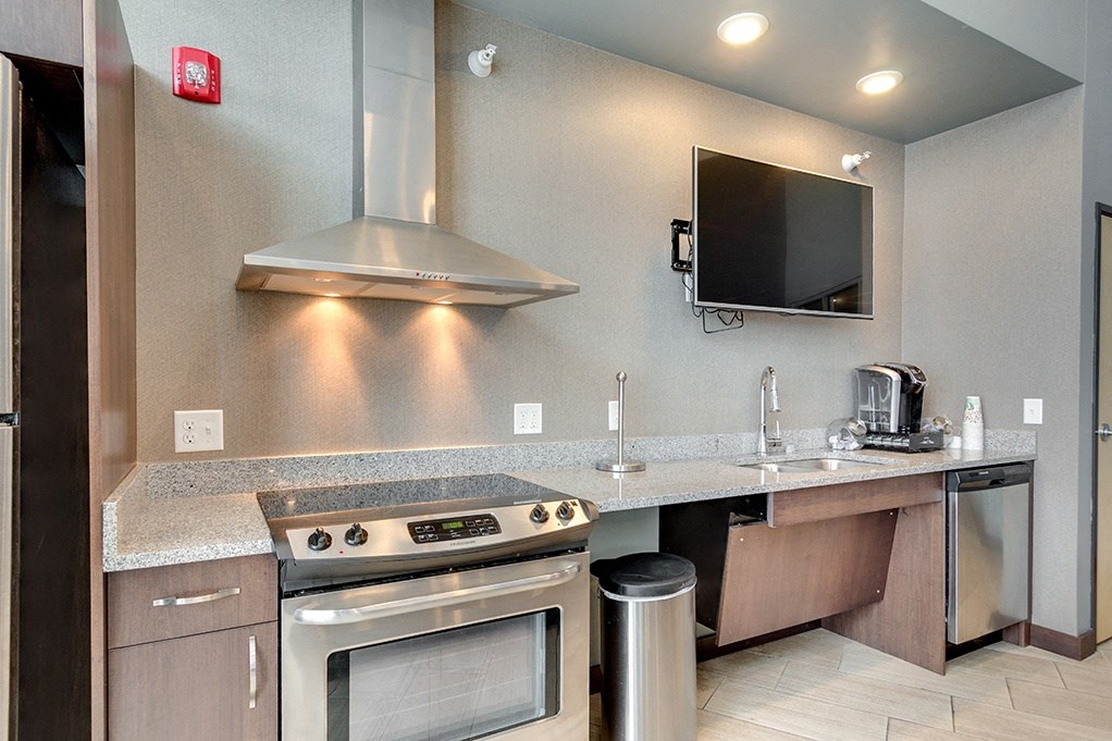 a kitchen with stainless steel appliances and a counter with a stove and a television