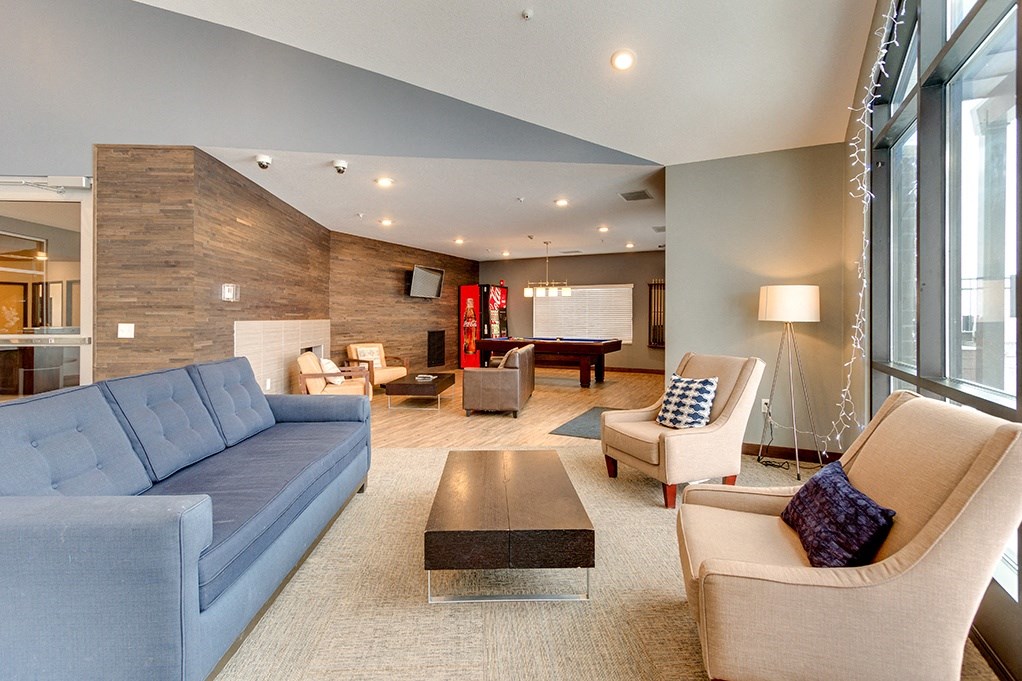 a living room with a blue couch and chairs and a pool table