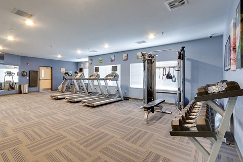 a gym with treadmills and weights and a staircase