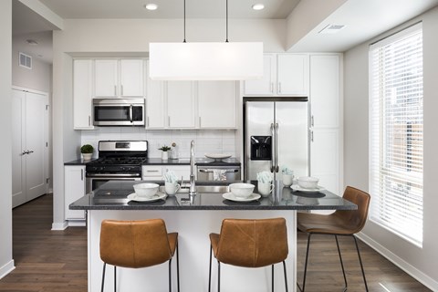 a kitchen with white cabinets and a counter top with chairs