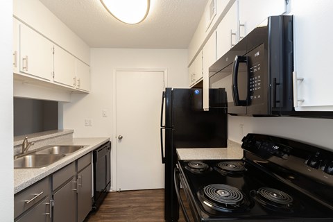 A kitchen with black appliances and white cabinets.