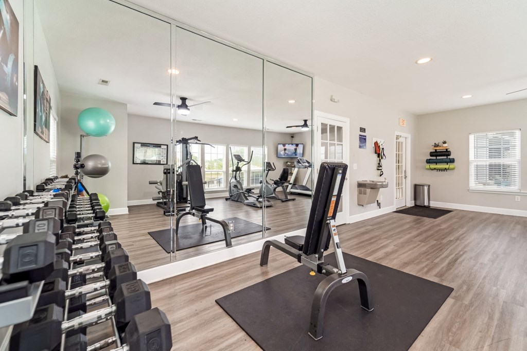 a gym with cardio equipment and mirrors at the bradley braddock road station apartments