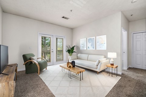 A living room with a white couch, a green chair, and a wooden coffee table.