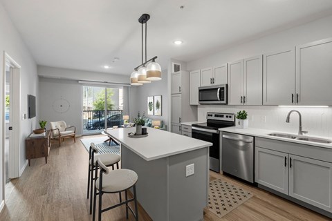 A modern kitchen with a large island and a dining area.