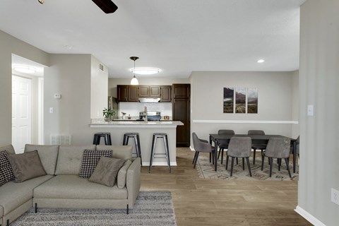 A living room with a grey couch and a dining table with chairs.