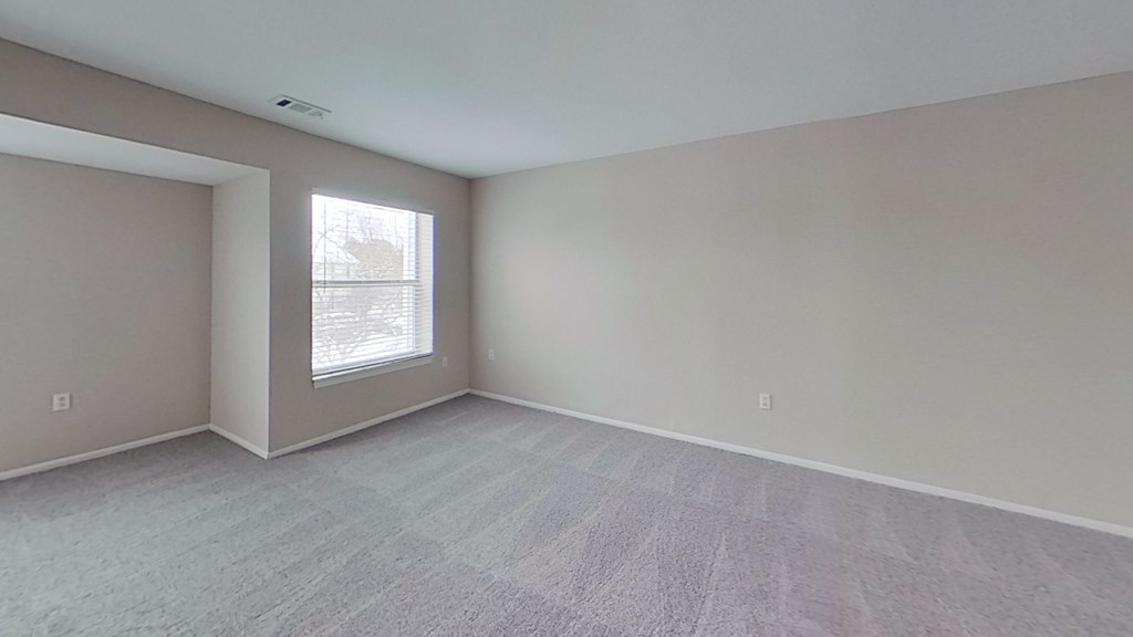 A room with a large window and a carpeted floor.