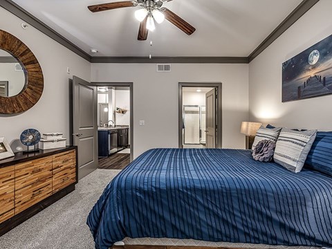 A bedroom with a bed, dresser, mirror, and a ceiling fan.