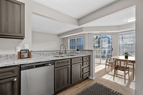 A kitchen with a dishwasher, sink, and a table with chairs.
