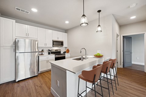 a kitchen with white cabinets and a large island with chairs
