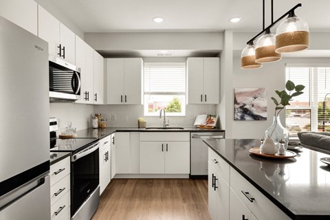 a kitchen with white cabinets and a black counter top
