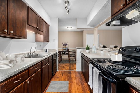 A kitchen with a black stove top oven and wooden cabinets.