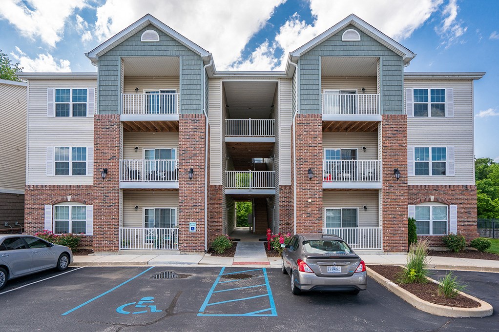 an apartment building with two cars parked in front of it