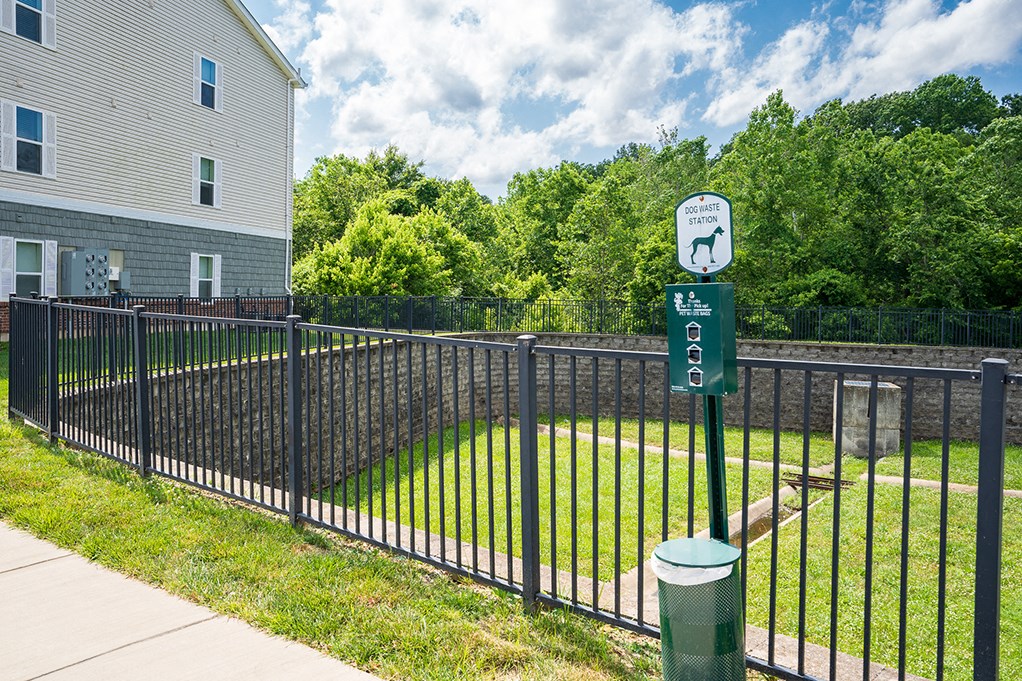 a black wrought iron fence surrounding a yard with a green sign on it