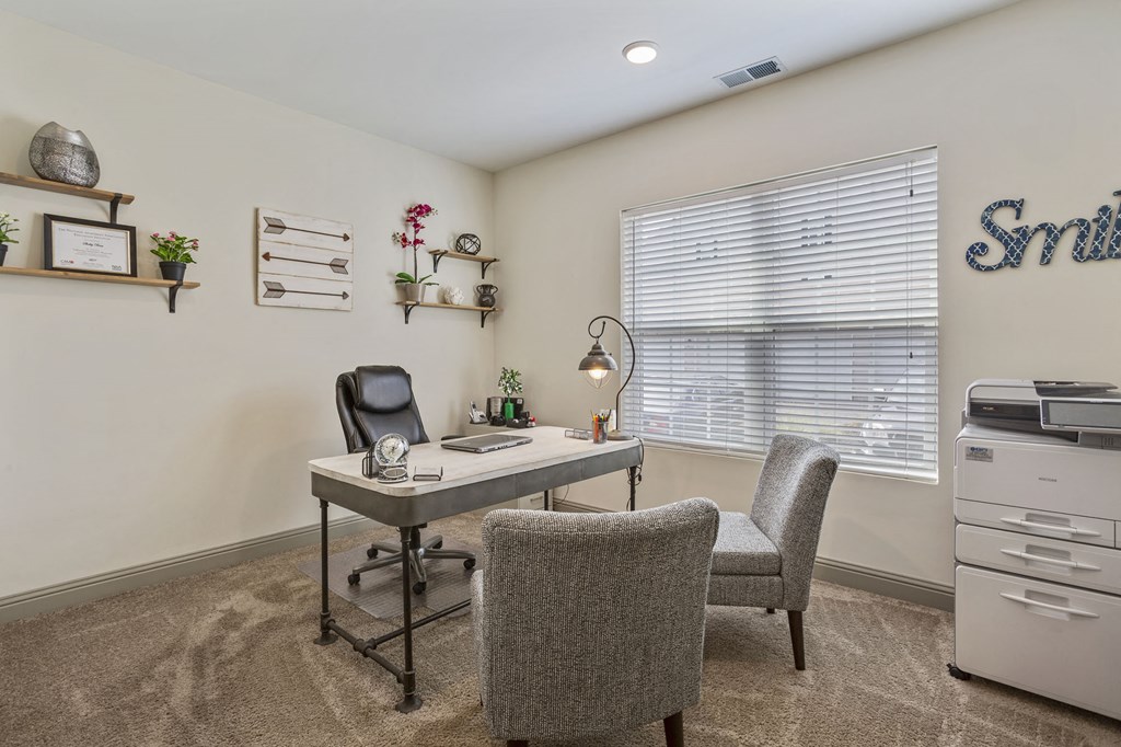 an office with a desk and chairs and a window