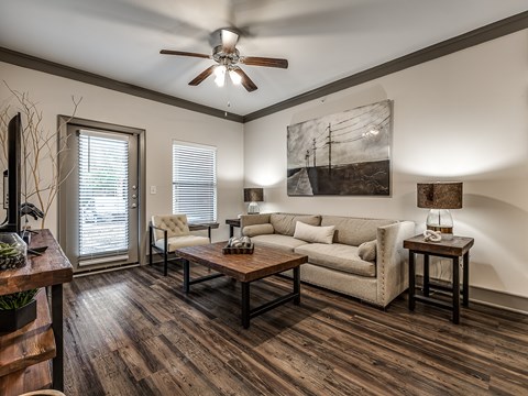 A living room with a couch, a chair, a coffee table, and a painting on the wall.