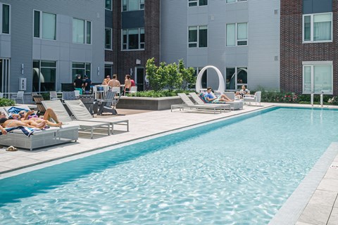 Pool surrounded by residents in lounge chairs
