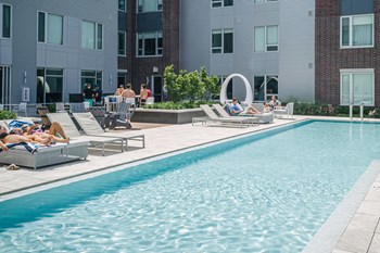Pool surrounded by residents in lounge chairs - Photo Gallery 13