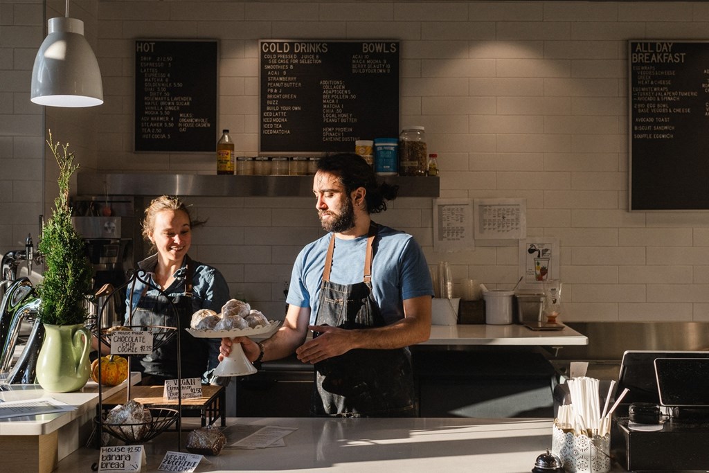 Workers organizing pastries behind counter at The Grocery market