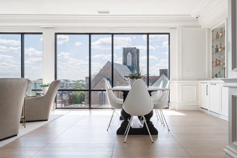 Lounge with modern dining table and chairs, bar and view of city out windows.