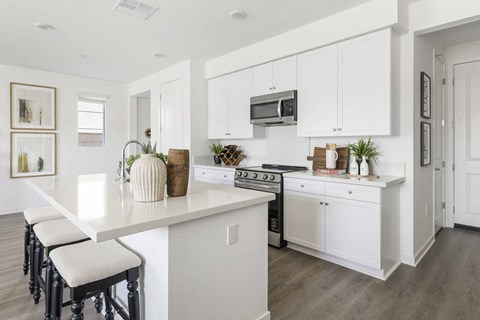 A white kitchen with a counter and stove top oven.