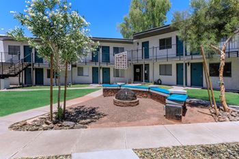 a courtyard with a fire pit and trees in front of a building