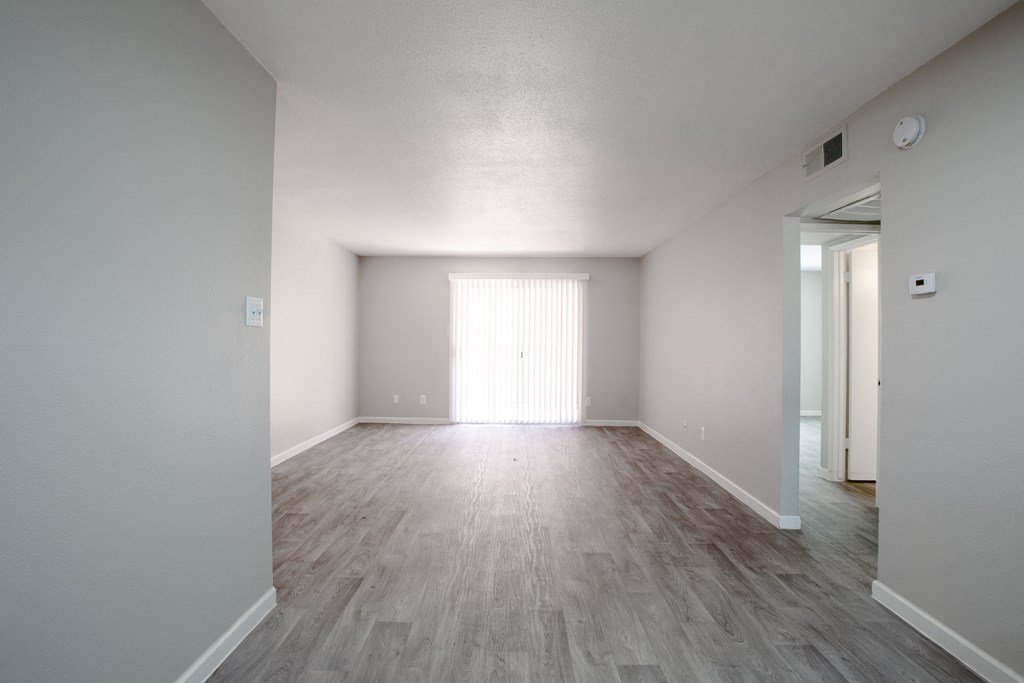 an empty living room with white walls and wood flooring at Ascent on Peoria Apartments, Phoenix