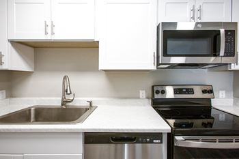 a kitchen with white cabinets and stainless steel appliances at Ascent on Pantano Apartments, Tucson