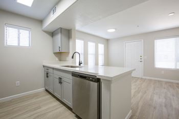 a kitchen with white cabinets and a large island with a stainless steel dishwasher at 60 at Melrose Apartments, Phoenix, AZ 85013