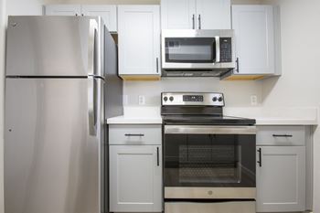 a kitchen with white cabinets and stainless steel appliances at 60 at Melrose Apartments, Phoenix, Arizona