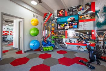 a workout room with a variety of exercise equipment and a large screen tv at The Vintage Apartments, Tucson