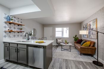 a kitchen with a sink and a counter top next to a living room with a couch and